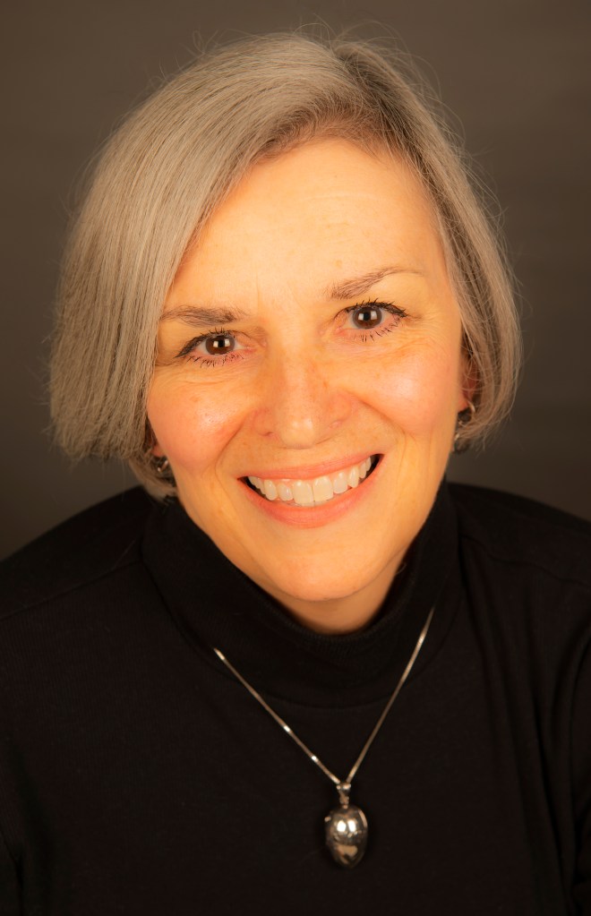 My headshot in black turtleneck with silver locket