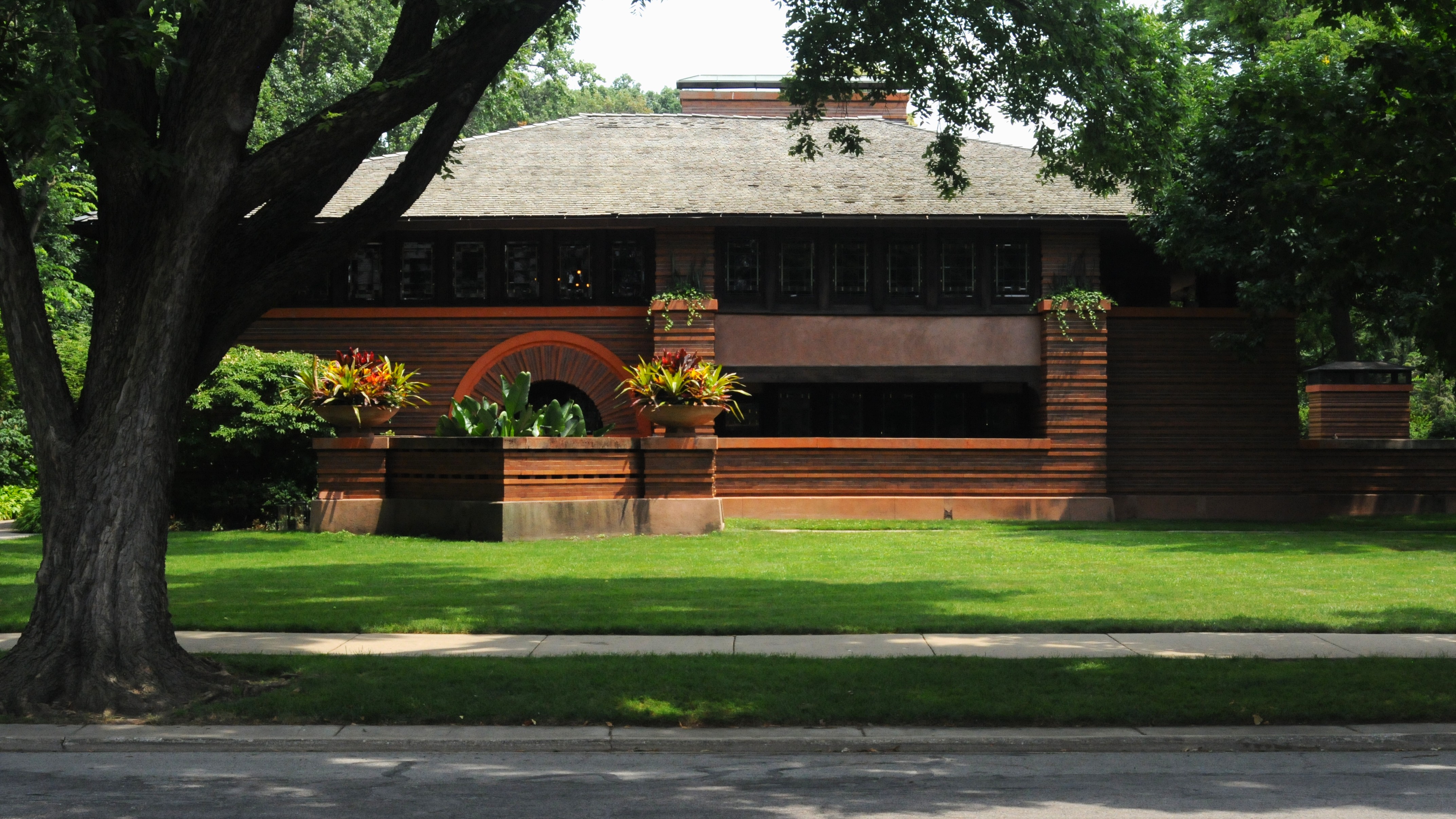 The Arthur Heurtley House (1902) shows the early emergence of Wright’s Prairie style. Notably, the ochre color palette explodes against the lush foliage that is everywhere in this neighborhood.
