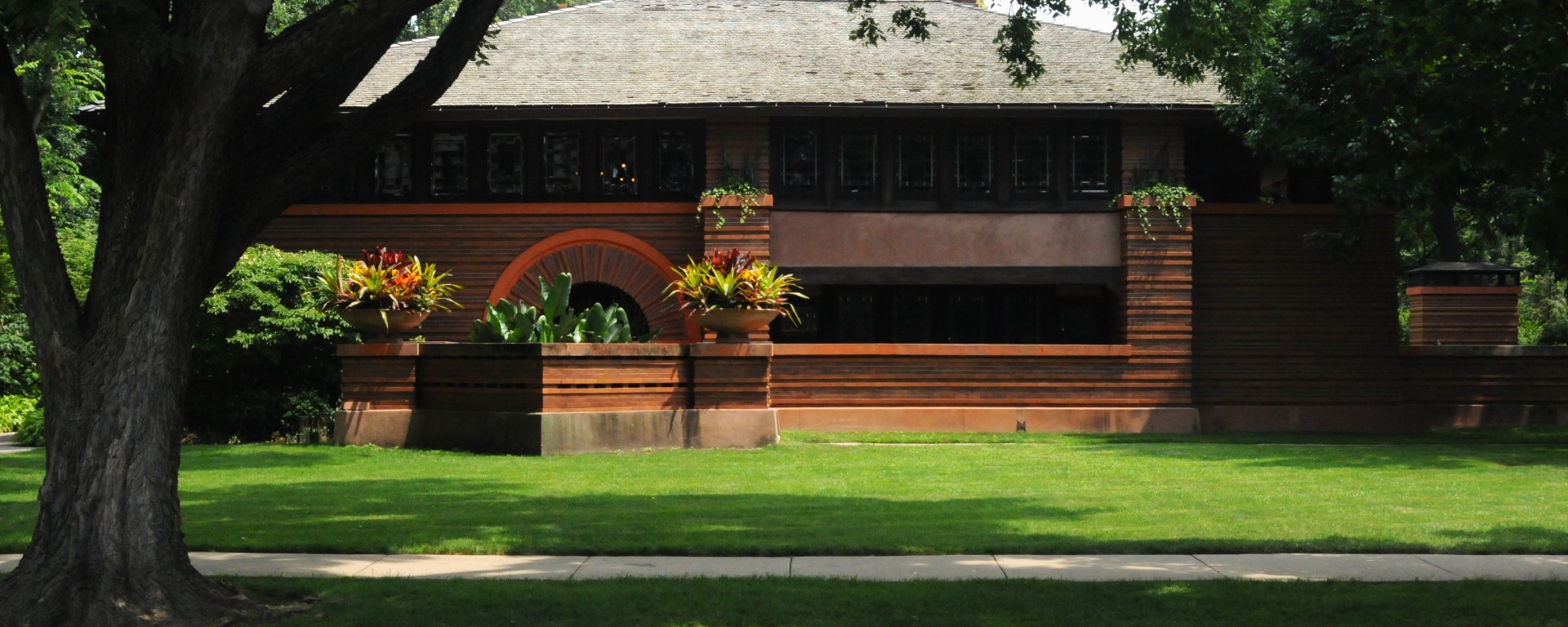 The Arthur Heurtley House (1902) shows the early emergence of Wright’s Prairie style. Notably, the ochre color palette explodes against the lush foliage that is everywhere in this neighborhood.